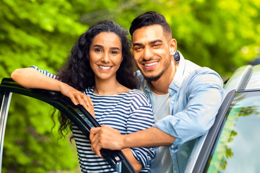Happy attractive multiracial lovers enjoying car trip to countryside, closeup portrait. Handsome arab guy hugging his pretty woman, standing by open auto door, hugging and smiling at camera photo