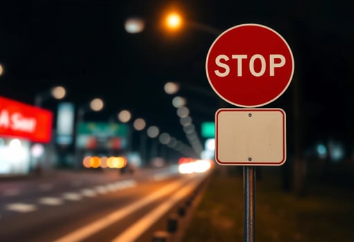 A red Stop sign and blank white sign, roadside warning sign, exhibiting a blurred bokeh effect of road photo