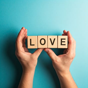 Hands holding wooden blocks spelling love on blue background photo