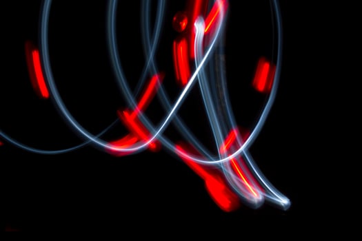 A photo with a long shutter speed of two lights moving. One light is white and one is red. The red one has flashed.