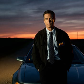 A man in a suit standing next to a car photo