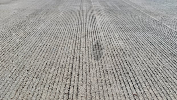 Stripes in Concrete A close-up view of a newly poured concrete surface with evenly spaced, deep grooves, creating a hypnotic pattern that speaks to the beauty of repetition and precision. photo