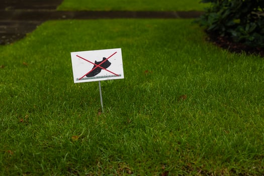 No walking on grass sign. Do not step on lawn warning symbol. Prohibition signpost on lawn. Forbidding harm to nature. Red and white road sign for environmental protection. Crossed out icon. photo