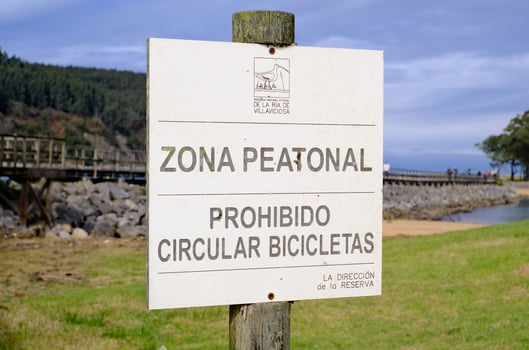 A sign on a post that says Zona Peatonal Prohibido Circular Bicicletas in Spanish photo