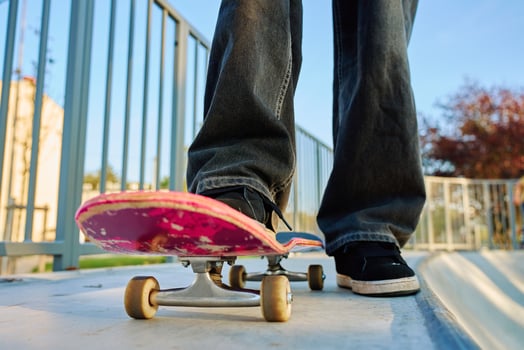 Teenager skateboarder riding on pink skateboard at skatepark photo