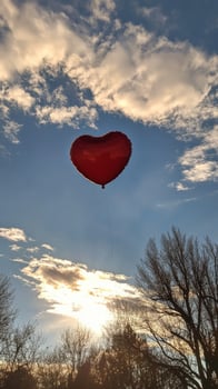 A heart shaped balloon is flying in the sky photo