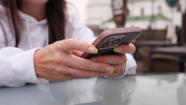 Closeup of hands gripping a smartphone outdoors, showcasing modern technology and lifestyle choices vividly photo