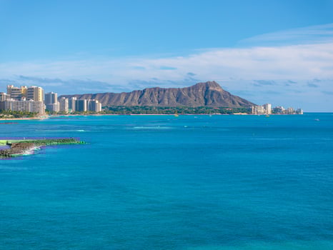 Turquoise Pacific waters meet Waikiki Beach's coastline, with high rise hotels and Diamond Head Crater under a clear blue sky in Honolulu, Hawaii. photo