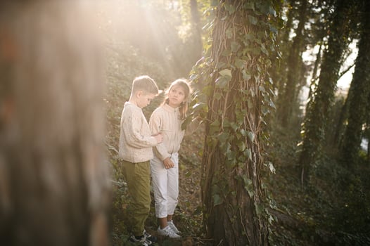 The forest glows with golden light as two young explorers study the creeping plants, mesmerized by natures quiet magic. photo
