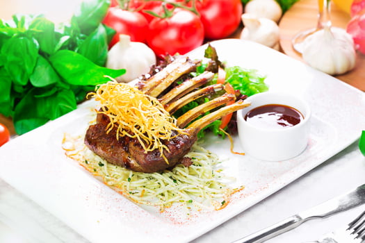 Elegant dish featuring grilled lamb chops served with greens and sauce at a fine dining establishment photo