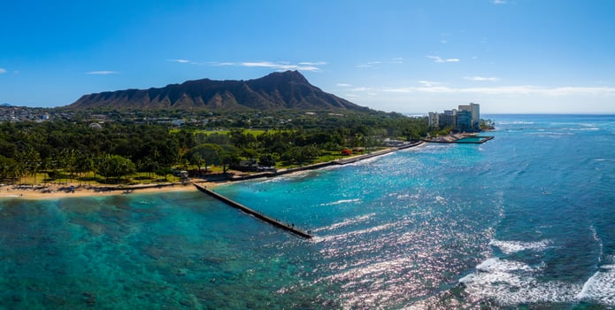 Aerial view of Oahu, Hawaii, featuring Diamond Head crater, turquoise Pacific waters, sandy beach, lush greenery, and buildings near the shoreline. photo