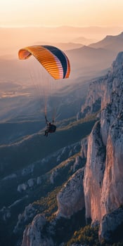 Paraglider flying over mountains at sunset photo