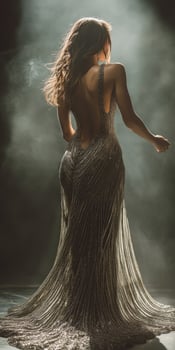 A woman in a silver dress is standing in the dark photo