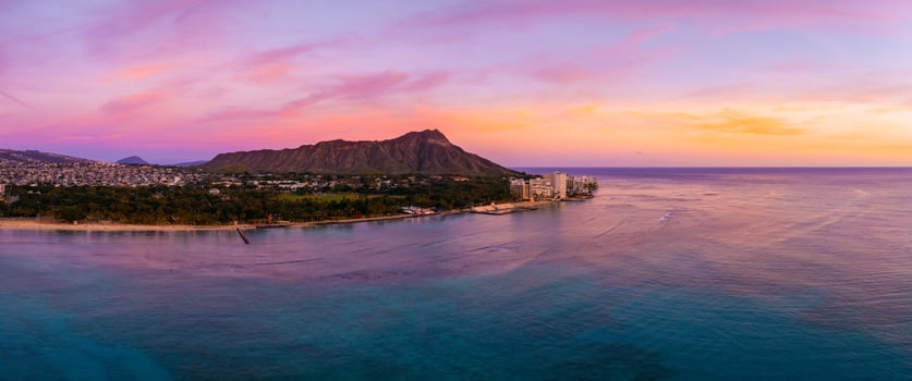 Aerial view of Waikiki Beach in Honolulu, Oahu, Hawaii, at sunset with Diamond Head Crater in the background and vibrant skies over turquoise waters. photo