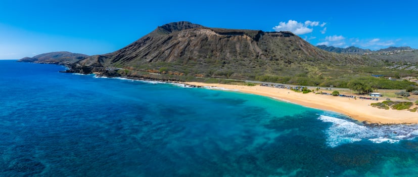 Aerial view of Oahu Island's beach with turquoise waters, golden sand, and Diamond Head crater in the background under clear blue skies. photo