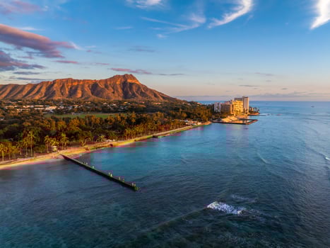 Aerial view of Waikiki Beach in Oahu, Hawaii, at sunset with Diamond Head Crater in the background, turquoise waters, sandy shoreline, and coastal buildings. photo