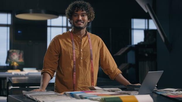 Portrait of happy Indian Arabian man cloth designer at modern tailoring dressmaking studio smiling male tailor couturier in garment workshop small business hand craft fashion fabric clothing design photo