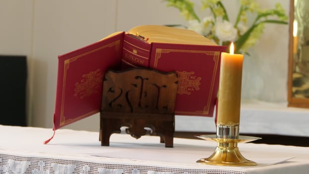 a candle and book on a table in front of a white altar photo