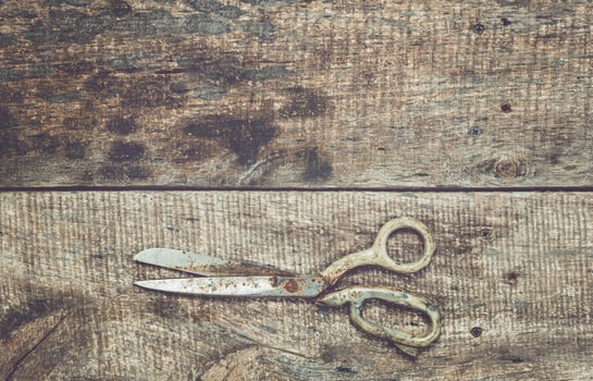 Scissors lying on rustic wooden surface with natural grain patterns, indicative of a crafting or DIY project in progress photo