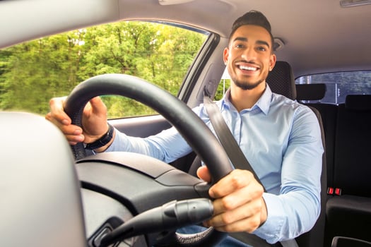 Smiling arab guy going to office in the morning, driving his car, copy space, shot from dashboard. Cheerful middle-eastern young man looking at the road, sitting inside luxury automobile, going home photo