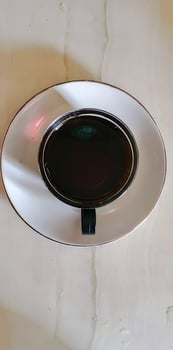 A white plate with a black rim and a black liquid photo