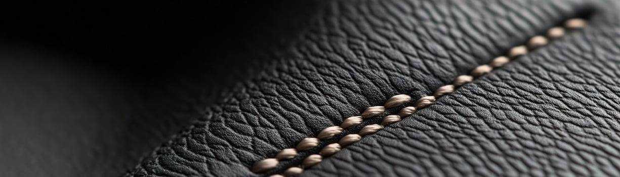The refined black leather surface showcases a soft-focus design, featuring a subtle pattern of raised stitching that enhances its elegance. This texture creates an ideal backdrop for branding or text photo