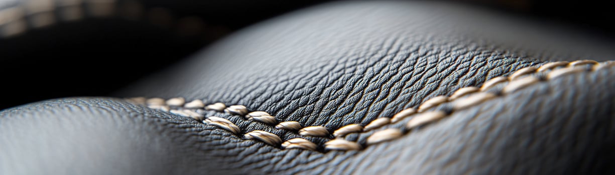 Soft-focus black leather surface features intricate raised stitching that adds a touch of sophistication, making it ideal for luxury branding applications or design projects photo