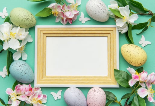 Easter eggs and flowers bordering a blank frame on a turquoise background photo