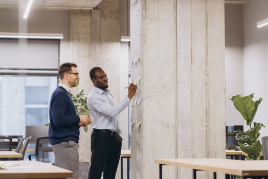Diverse businesspeople collaborating, noting strategic concepts on glass wall, representing innovative workplace communication and team synergy photo