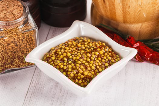 A bowl of mustard seeds and a bottle of mustard photo