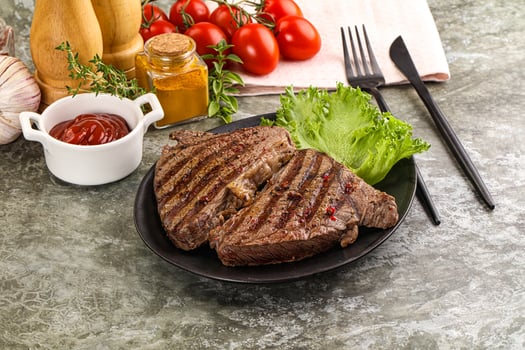 A plate of steak with tomatoes and ketchup on it photo