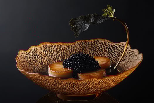 Golden-brown seared scallops with yuzu beurre blanc and black caviar pearls on a dark backdrop photo