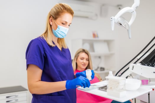 Dentist is repairing teeth of young woman. She is preparing dental filling. photo