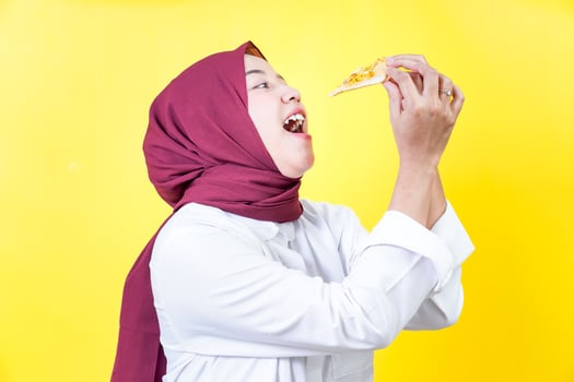asian woman eating pizza isolated on yellow background photo