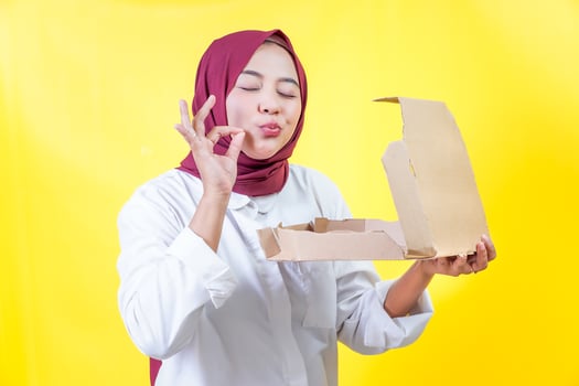 A young asian woman enjoys delicious pizza, showing approval with a playful gesture photo