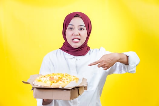 a woman in a white shirt holding and pointing to box of a pizza photo