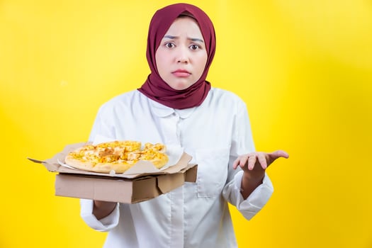 an asian woman posing wondered in a white shirt holding a pizza box against a vibrant yellow background photo