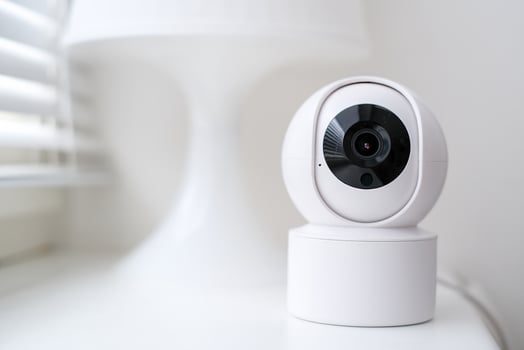 Smart home security camera on a white table near a window. photo