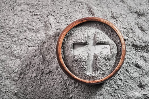 Cross imprint in gray ash bowl on ash background. Ash Wednesday photo