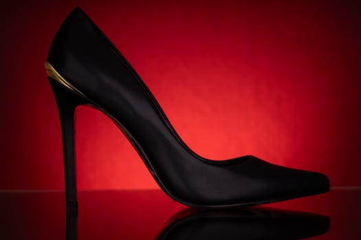 Elegant Black High Heel with Gold Detail on Red Background photo