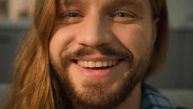 Close up Caucasian bearded man male guy sleeping napping relaxing leaning couch sofa wake up looking at camera smiling happy laughing smile positive face portrait laugh satisfied indoors joy fun funny photo