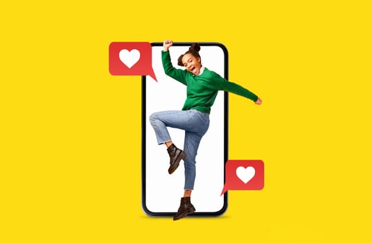A young woman joyfully interacts with a smartphone, expressing excitement about social media connections and messages of love. Vibrant yellow background highlights her energy and enthusiasm. photo
