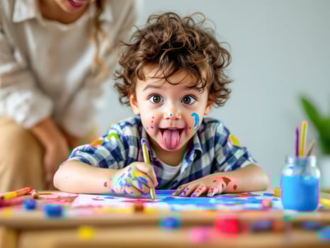 Curly child draws with paints under the guidance of mom photo