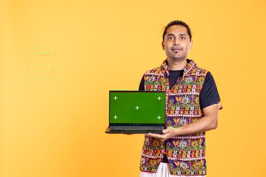 Portrait of smiling man holding green screen laptop, doing important work for company, isolated over studio background. Employee with mockup on notebook device, isolated over studio backdrop photo