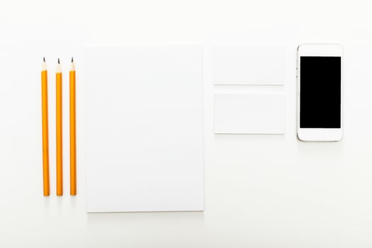 Workspace setup with pencils, blank notepad, business cards, and smartphone on clean surface photo