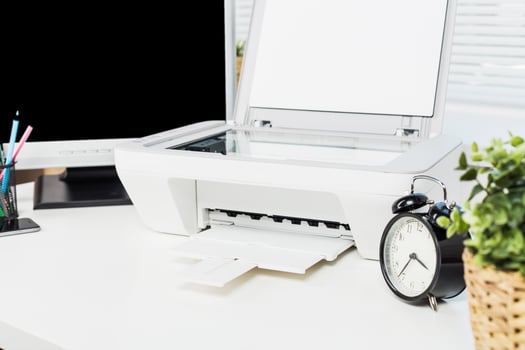 Desk setup features a printer, clock, and plants in a bright workspace promoting productivity and organization photo