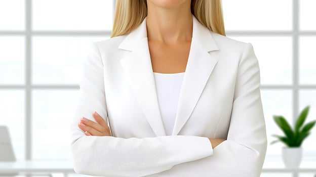 Confident businesswoman in a white suit standing with arms crossed in a modern office setting photo
