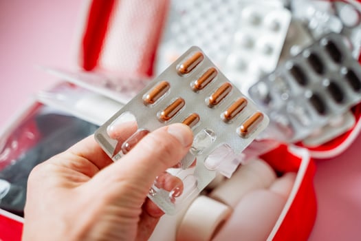 A person has a blister pack of pills held securely in their hand, clearly showing the small compartments that generally contain the medication that is packaged within it safely photo