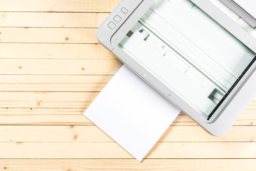 Scanner ready to process white paper against a wooden tabletop in a well-lit workspace photo