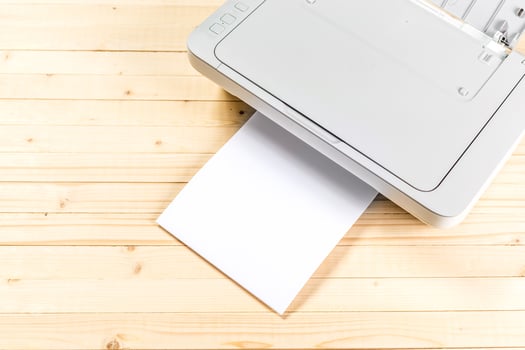 Printer producing a blank sheet of paper on a wooden surface during a quiet afternoon in a home office setup photo